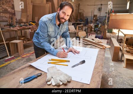 Smiling young man as an architect with architectural drawing during a project planning Stock Photo