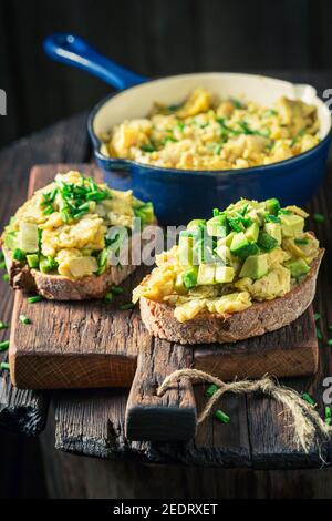 Tasty and homemade fried eggs with chive and avocado on wooden board Stock Photo