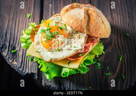 Delicious burger with lettuce, fried egg and bacon on white table Stock Photo