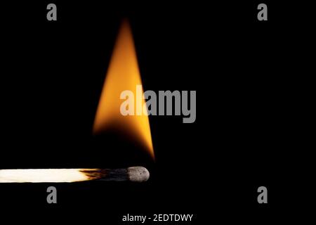 Close-up of a burning matchstick against a black background. Stock Photo