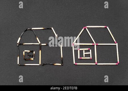 Two match houses made of burnt and unburnt matchsticks on a black background.Creative flat lay composition. Fire insurance coverage concept. Stock Photo