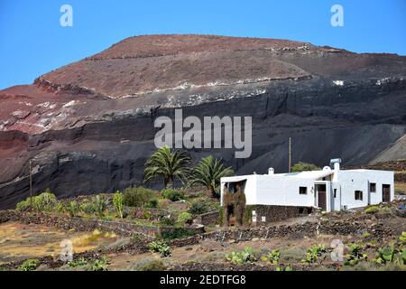 Beautiful volcanic landscape with a white house in front. Lanzarote, Canary Islands, Spain. Caldera de Masion near Femés. Image taken from public grou Stock Photo