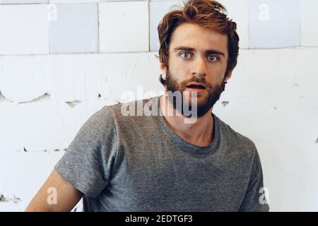 Expressive young bearded man scared and nervous Stock Photo