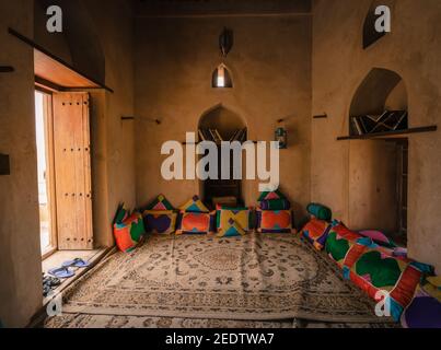 Nakhal, Oman - 04.03.2018: Room of a medieval arabian castle. Carpets and pillow on the floor, holy books on the shelf. Fort of Nakhal, Oman. Stock Photo