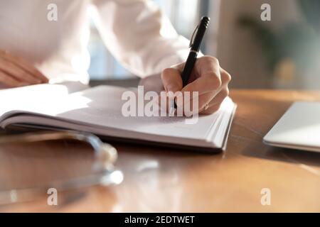 Close up young female physician therapist making notes. Stock Photo