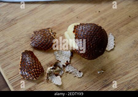 an indonesian salak or snake fruit on a wooden chopping board partly peeled Stock Photo