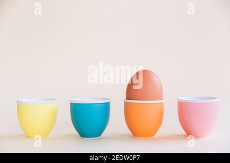 One brown egg standing on egg cup on pastel background, copy space. Easter minimal concept. Close-up Stock Photo