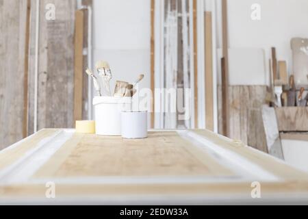 wooden workshop, paint brushes and color cans over a wooden door, isolated on a woodwork wall background with copy space, wood crafts, interior design Stock Photo