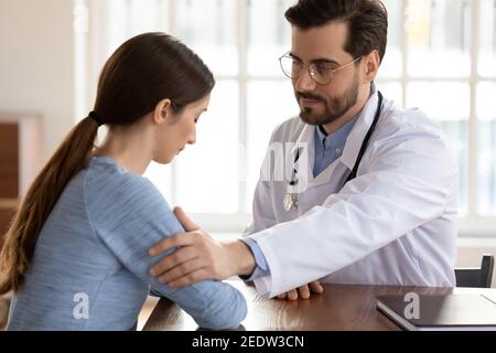 Compassionate kind young male doctor supporting depressed patient. Stock Photo