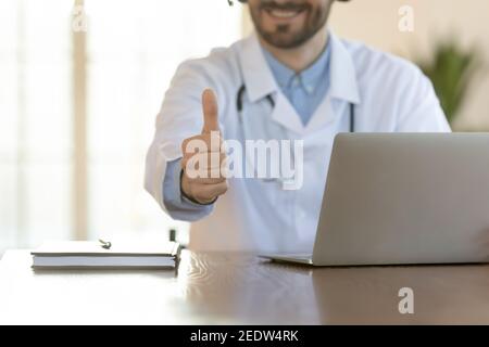 Close up smiling young male doctor showing thumbs up gesture. Stock Photo