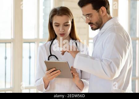 Two professional general practitioners colleagues discussing health treatment. Stock Photo