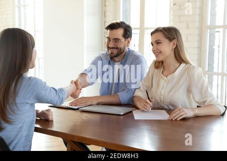 Smiling young human resources managers shaking hands with job applicant. Stock Photo
