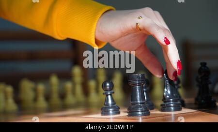 Closeup of an elegant female's fingers holding the knight piece on the chessboard Stock Photo