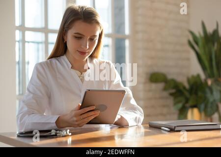Smiling attractive young female doctor using computer tablet. Stock Photo