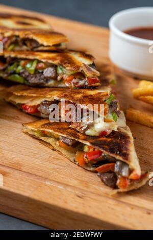 Mexican quesadilla with meat, cheese and peppers on wooden table. Stock Photo