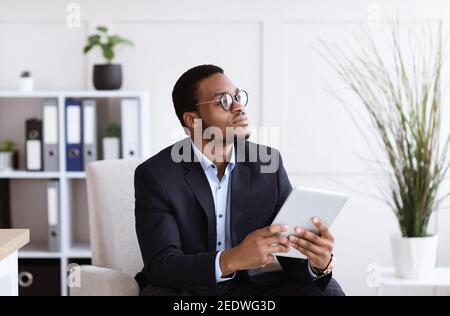 Pensive african american young businessman using digital tablet in office Stock Photo