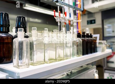 Transparent and brown glass flask for chemicals on a shelf, scientific research background, industry concept, chemistry laboratory Stock Photo