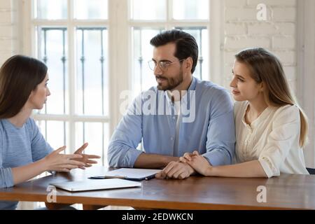 Happy young family couple visiting female real estate agent. Stock Photo