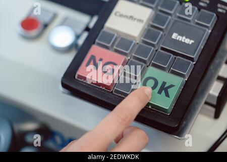 Factory worker pressing the OK button on a machine Stock Photo