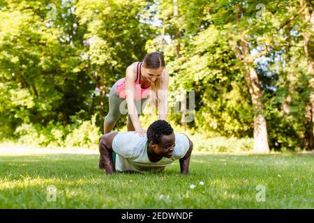 Mixed race couple doing fitness pushups in the park Stock Photo