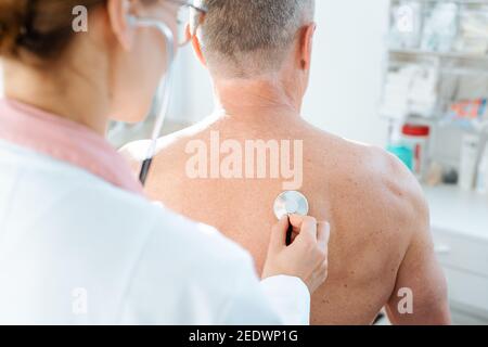 Doctor using stethoscope to check lung function of man Stock Photo
