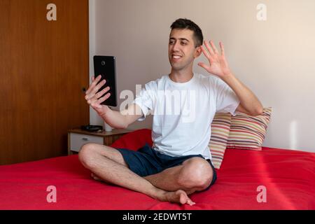 Young man on a video call with his tablet from bed Stock Photo