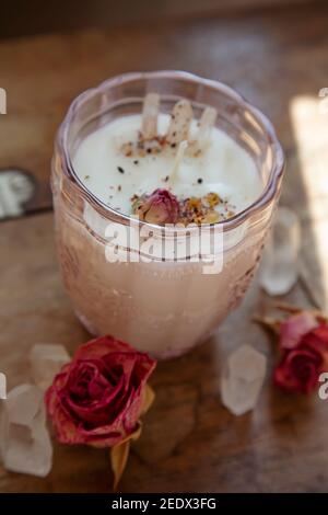 Soya candle with crystal quartz and rose decoration on vintage wooden table Stock Photo