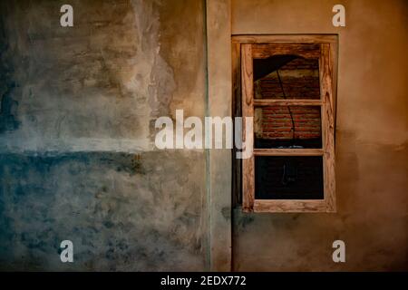 Half open wooden window on yellow brown grained plastered wall. Stock Photo