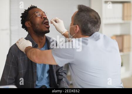 Portrait of young African American man taking covid test in vaccination center or clinic, copy space Stock Photo