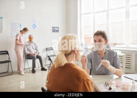 Wide angle view at young female doctor taking covid tests in clinic or vaccination center, copy space Stock Photo