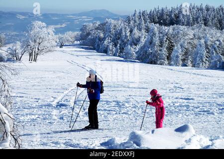 Father with daughter, Man child on a mountain meadow Cross country skiers winter scene skiing in Czech mountains Stock Photo