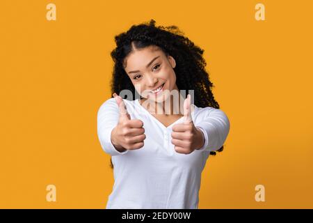 Positive Black Lady With Curly Hair Showing Thumbs Up At Camera Stock Photo