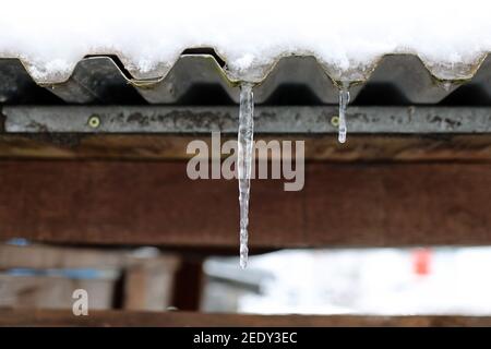 Snow on the roof melts and forms icicles Stock Photo