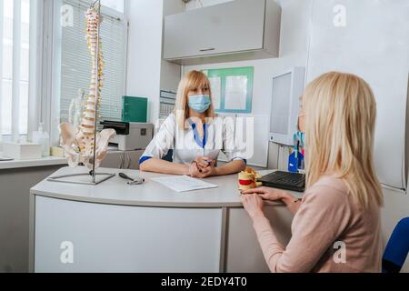 Female patient talking to doctor about her problems with her back during consultation Stock Photo