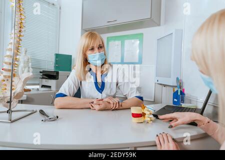 Female patient talking to doctor about her problems with her back during consultation Stock Photo