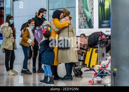 London, UK. 15th Feb, 2021. A large family group arrives and is met by many family members with hugs and flowers - People are still flying via Heathrow, on the day the new quarantine restrictions come in to force for international travel from a red list of countries. National Lockdown 3 is in force with the Government instruction for everyone to stay at home. Credit: Guy Bell/Alamy Live News Stock Photo