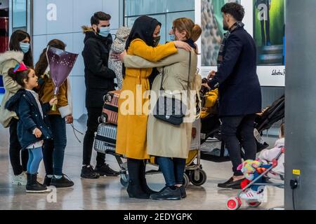 London, UK. 15th Feb, 2021. A large family group arrives and is met by many family members with hugs and flowers - People are still flying via Heathrow, on the day the new quarantine restrictions come in to force for international travel from a red list of countries. National Lockdown 3 is in force with the Government instruction for everyone to stay at home. Credit: Guy Bell/Alamy Live News Stock Photo