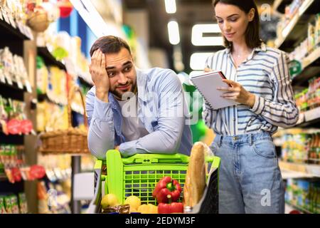 Funny young couple with shopping list in supermarket Stock Photo