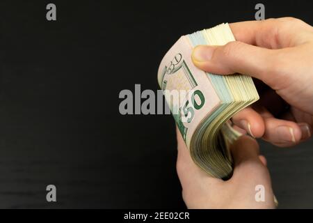 Women's hands move through a stack of hundred-dollar bills on a dark background close-up with copy space Stock Photo