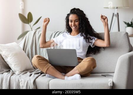 Emotional young woman using modern laptop at home Stock Photo