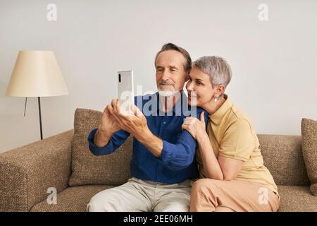 Senior couple spending time at home together. Elderly people taking a selfie while sitting Stock Photo