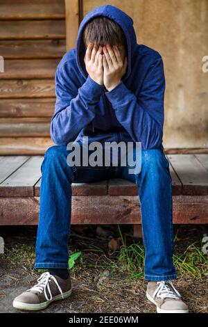 Sad Young Man in a Hoodie near the House Stock Photo