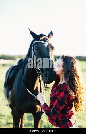 Black horse kissed by a young woman. Human and animal bond. Friendship. Stock Photo