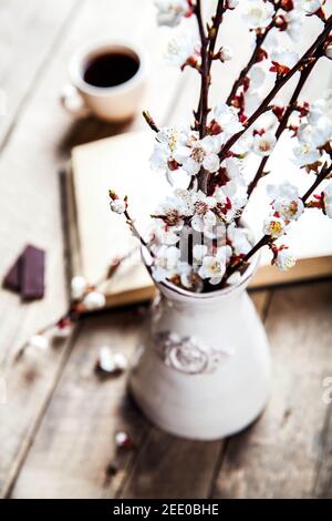 Open vintage book with blossom branch of cherry-tree on wooden table with a beautiful vintage vase and Stock Photo