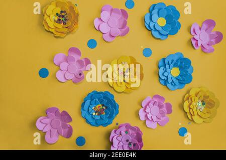 view from above on colorful paper flowers on yellow background Stock Photo