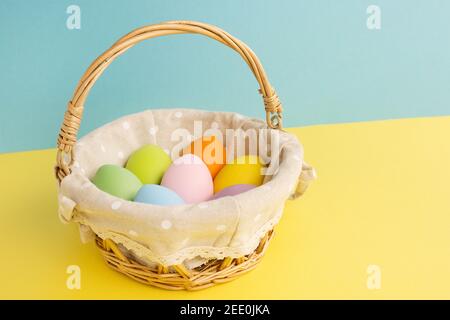 Basket with Easter colorful eggs on yellow blue background. Happy Easter concept Stock Photo