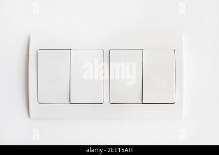 Four white light switches on a white wall in a close up view Stock Photo
