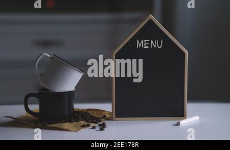 Menu text on blank black chalkboard next to two cups and coffee beans. Copy space for text or artwork mockup Stock Photo