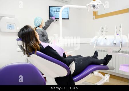 Health care concept - Female dentist showing x ray results on monitor to woman patient at dental clinic office. High quality photo Stock Photo