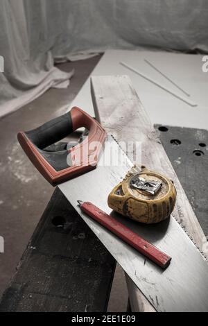 Hand saw, measuring tape and pencil on a piece of cut timber. Stock Photo